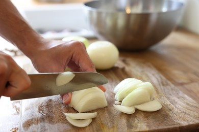 Photo of Woman cutting fresh ripe onion on wooden board, closeup. Space for text