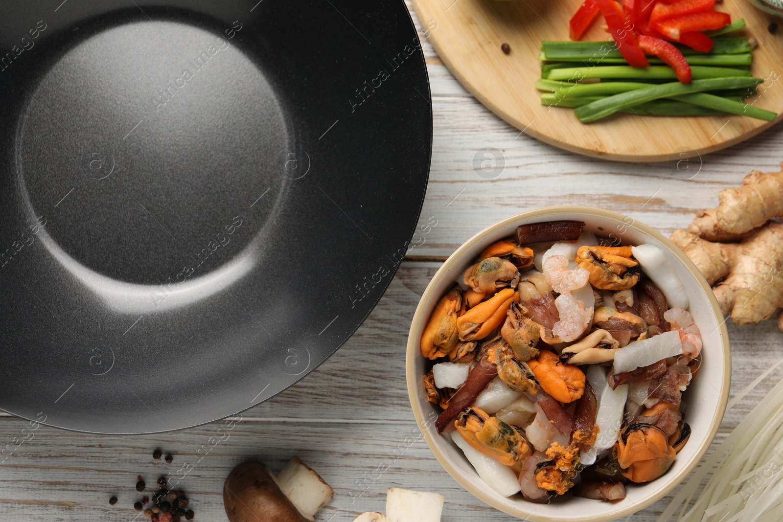 Photo of Flat lay composition with black wok and products on light wooden table