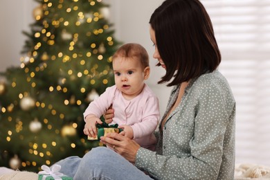 Photo of Happy young mother with her cute baby in room decorated for Christmas. Winter holiday