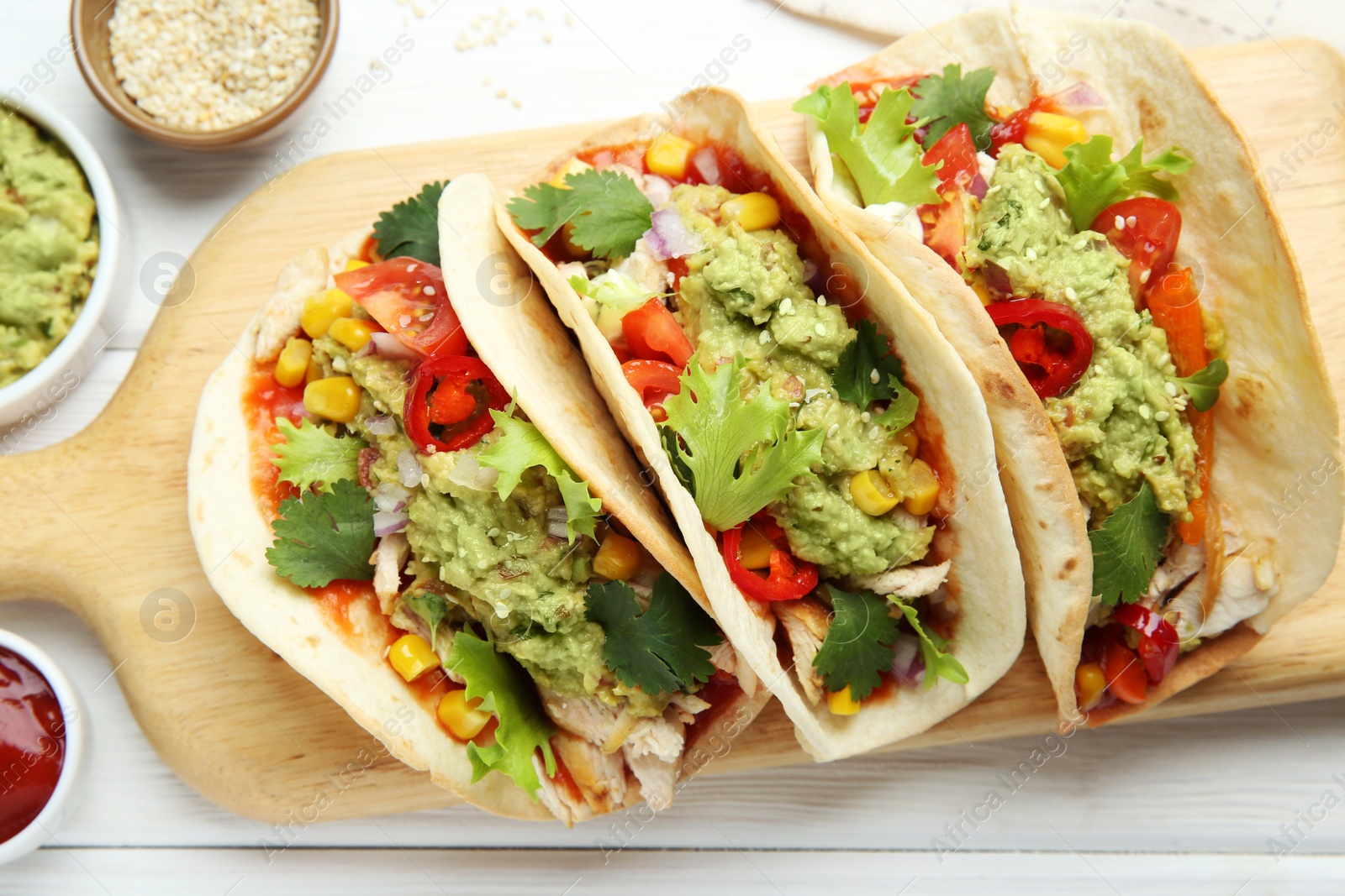 Photo of Delicious tacos with guacamole, meat and vegetables served on white wooden table, flat lay