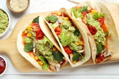 Photo of Delicious tacos with guacamole, meat and vegetables served on white wooden table, flat lay
