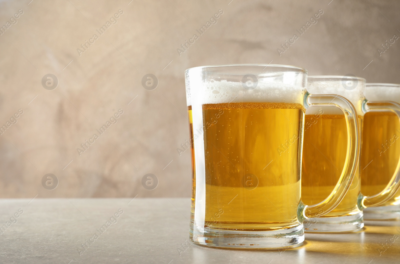 Photo of Glass mugs of cold tasty beer on table