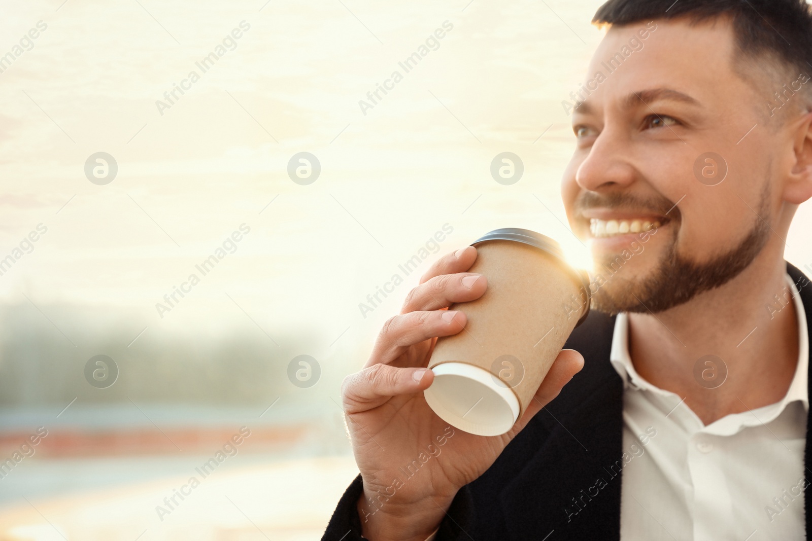 Photo of Man with cup of coffee on city street in morning