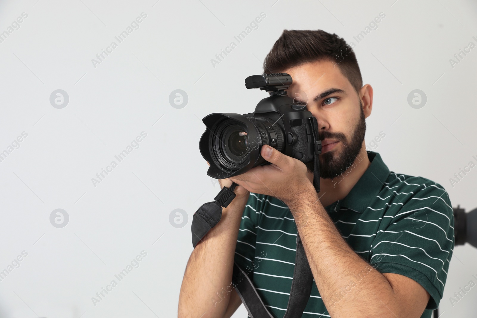 Photo of Young man with professional camera in photo studio. Space for text