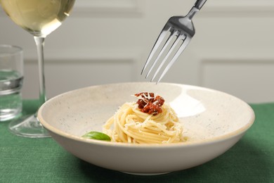 Photo of Eating tasty spaghetti with sun-dried tomatoes and cheese from plate at table, closeup. Exquisite presentation of pasta dish