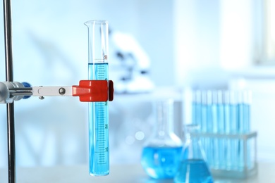 Photo of Graduated cylinder with light blue liquid in laboratory. Space for text