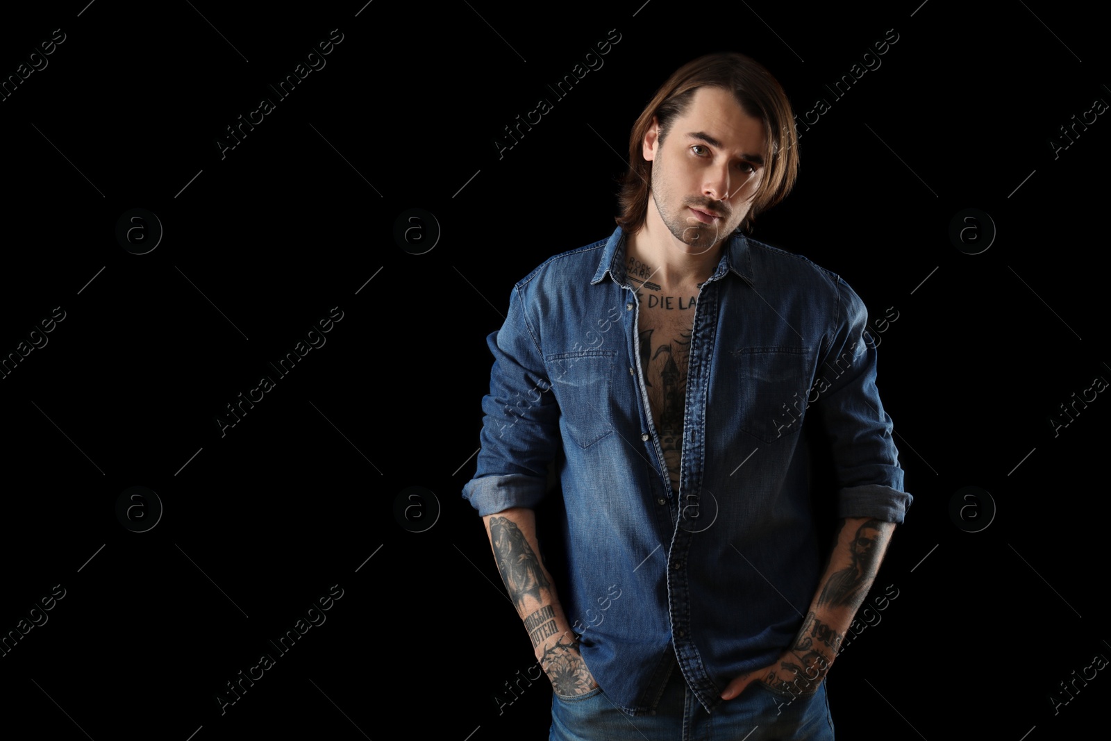 Photo of Young man with tattoos on body against black background. Space for text