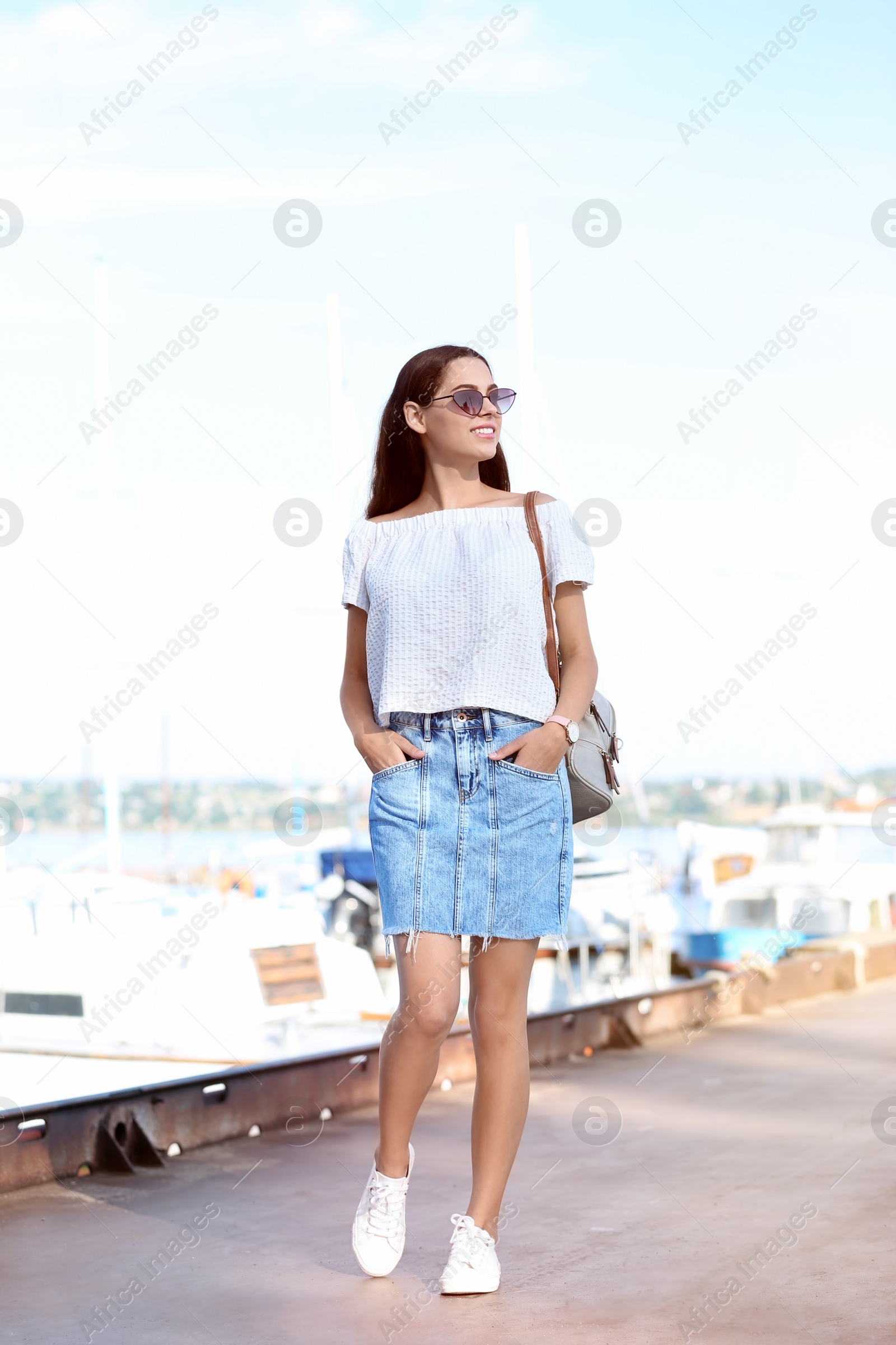 Photo of Young hipster woman in jean skirt on pier