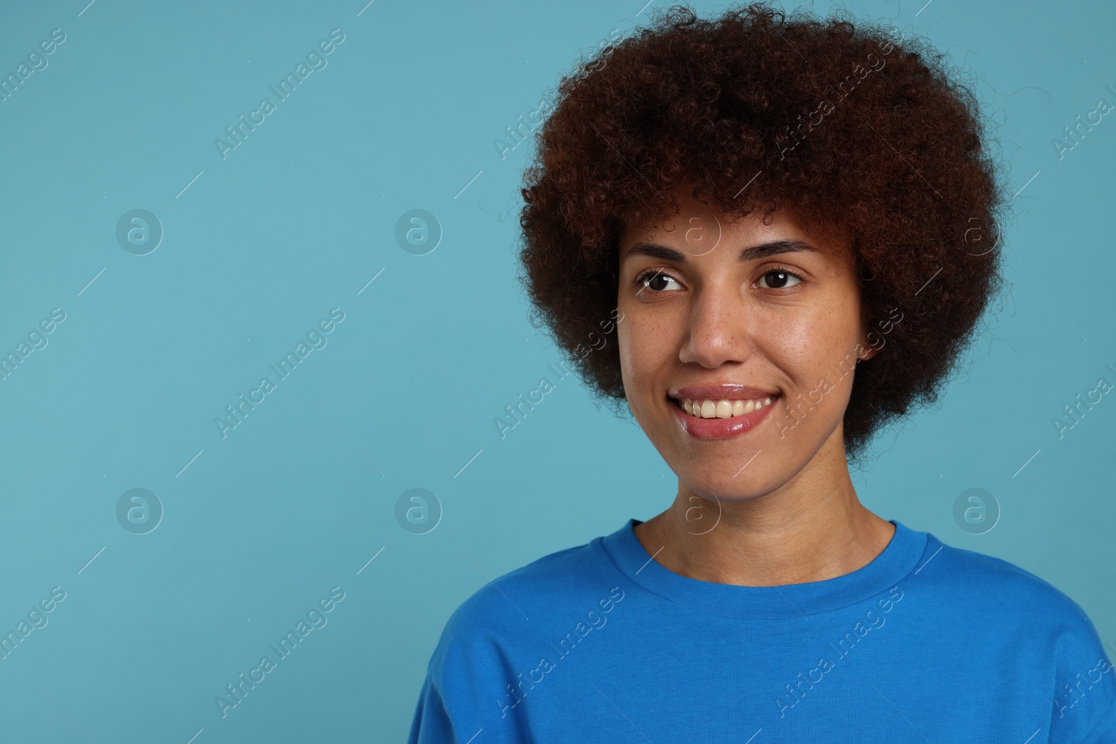 Photo of Portrait of happy young woman on light blue background. Space for text