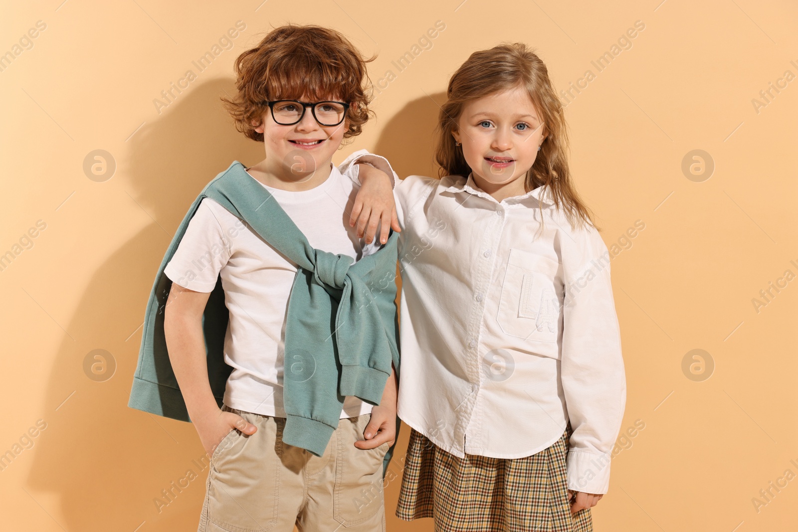 Photo of Fashion concept. Stylish children on pale orange background