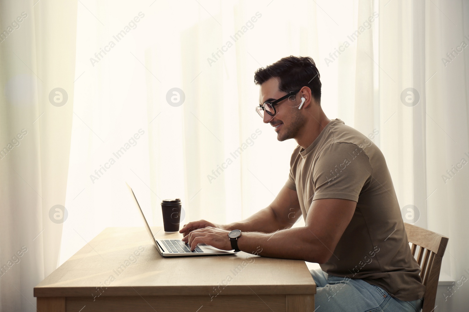 Photo of Portrait of young man with laptop at table indoors