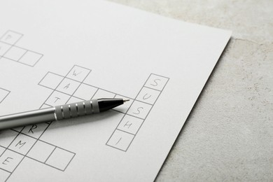 Photo of Crossword with answers and pen on old white table