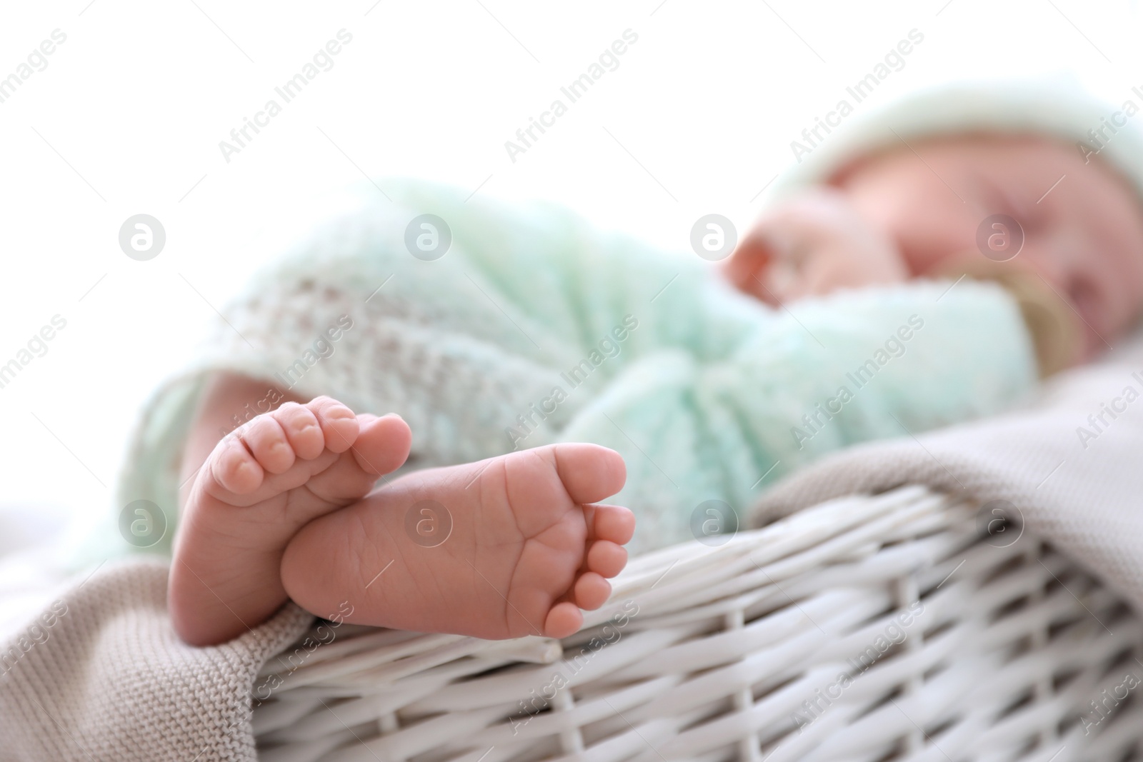 Photo of Newborn baby lying on plaid in basket, closeup of legs. Space for text