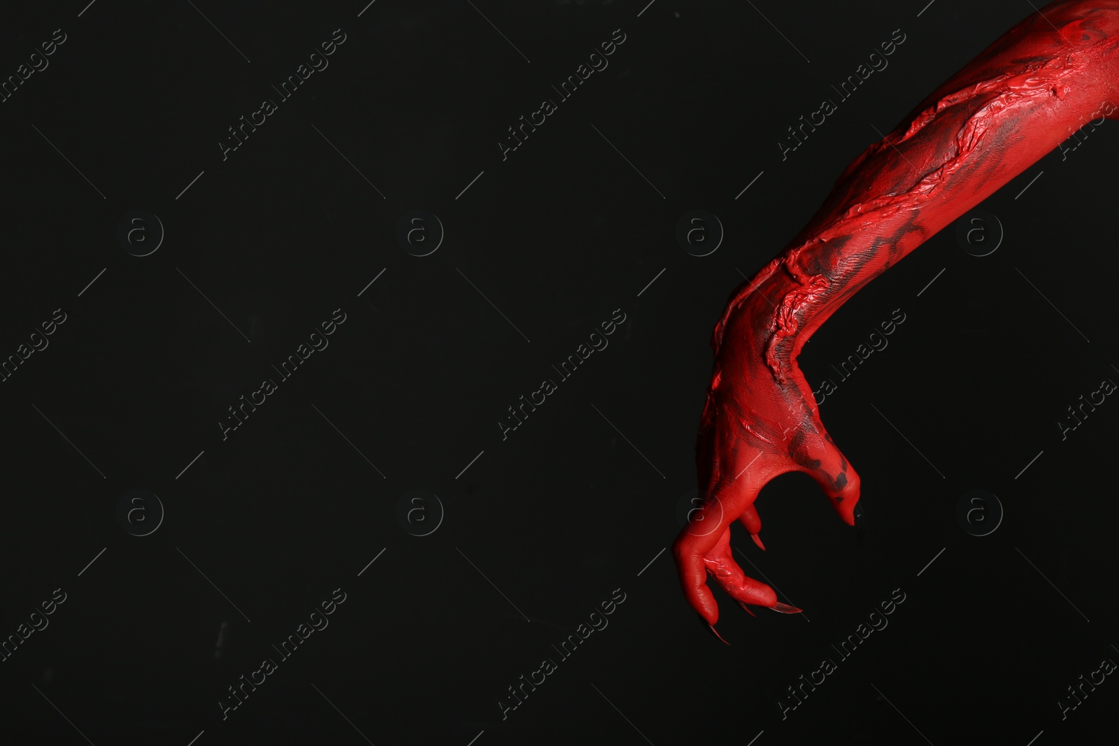 Photo of Scary monster on black background, closeup of hand with space for text. Halloween character