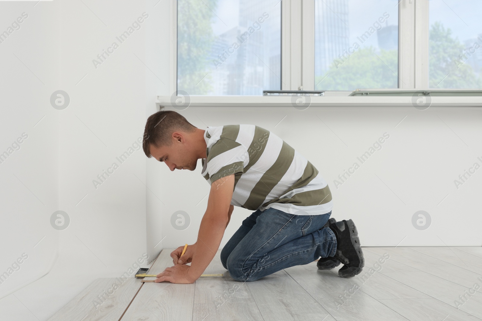 Photo of Professional worker installing new laminate flooring indoors