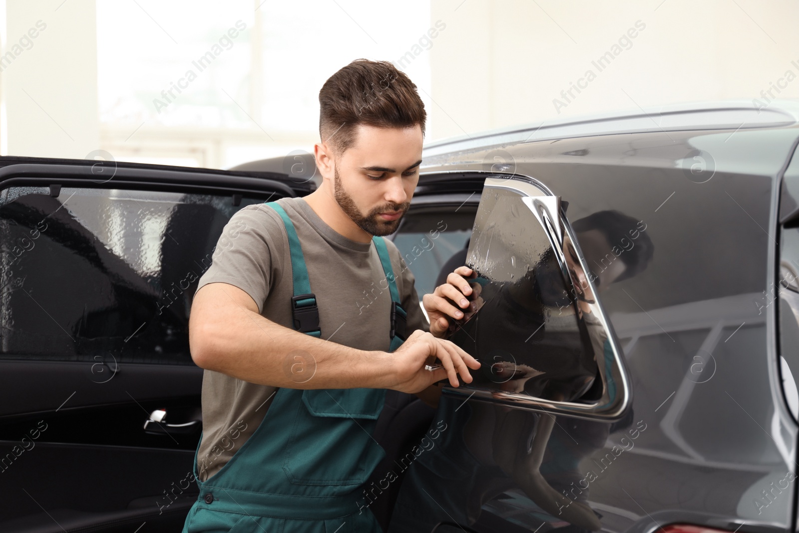 Photo of Worker tinting car window with foil in workshop