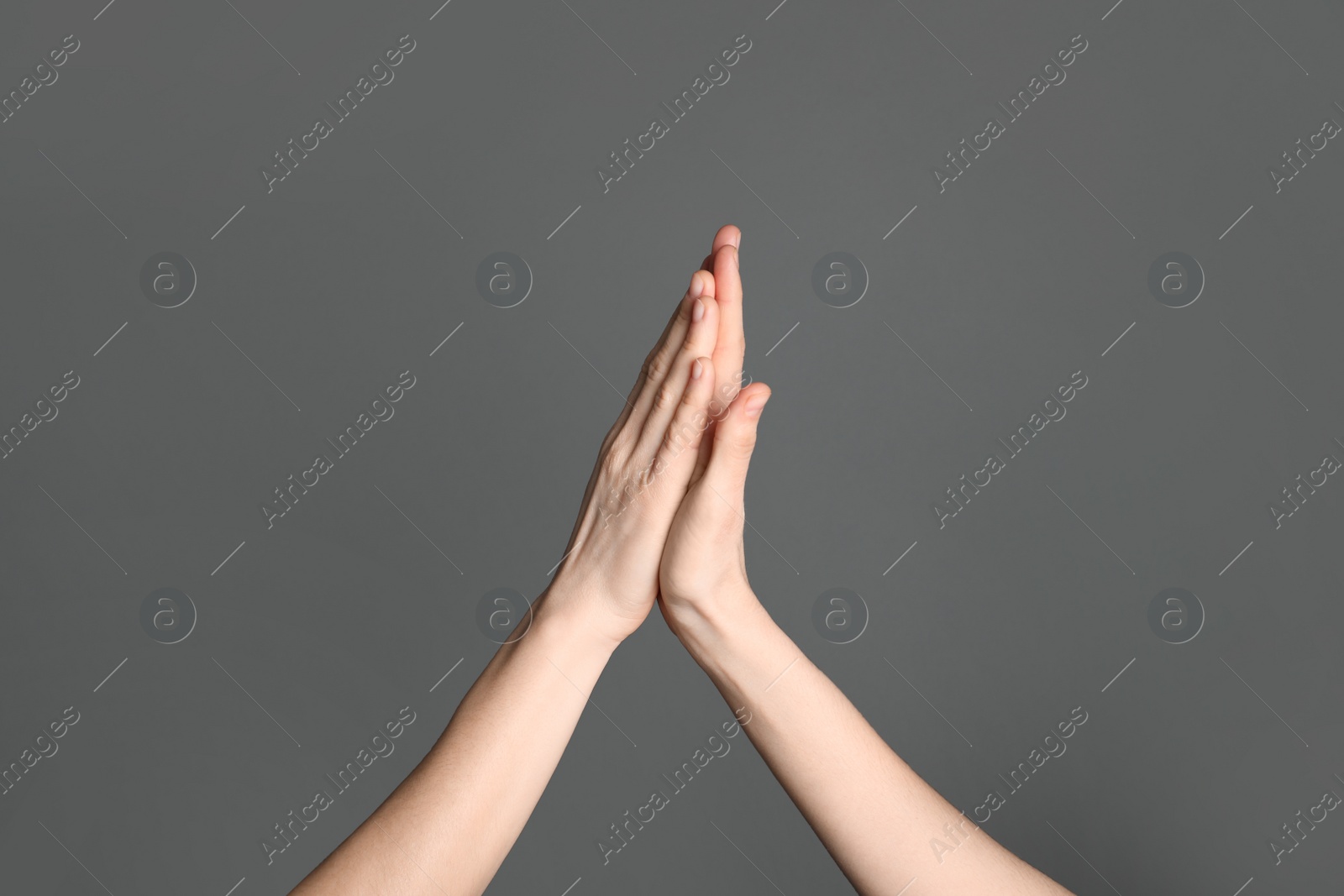 Photo of Women giving high five on grey background, closeup. Victory concept