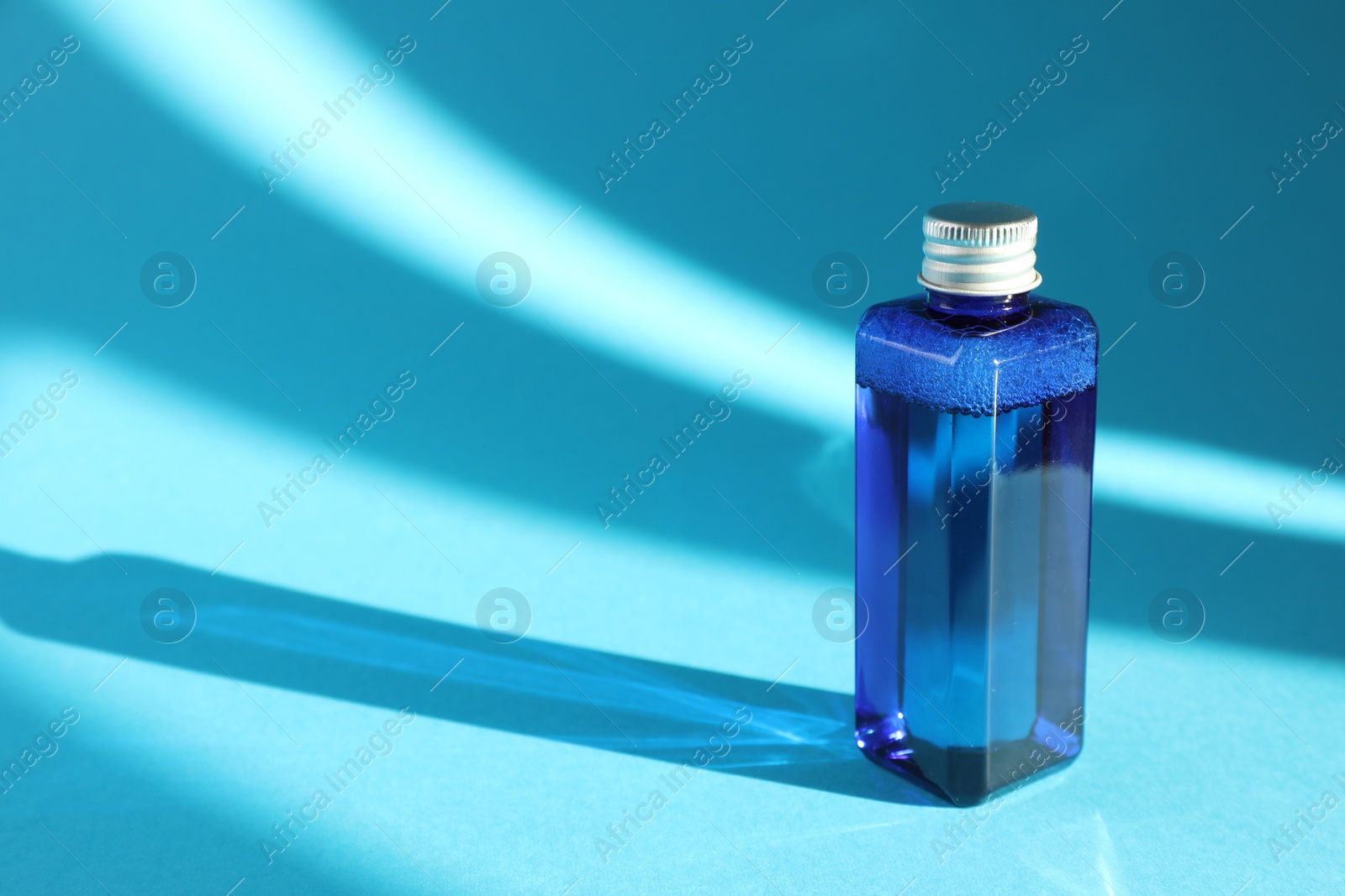 Photo of Bottle of cosmetic product on light blue background. Space for text