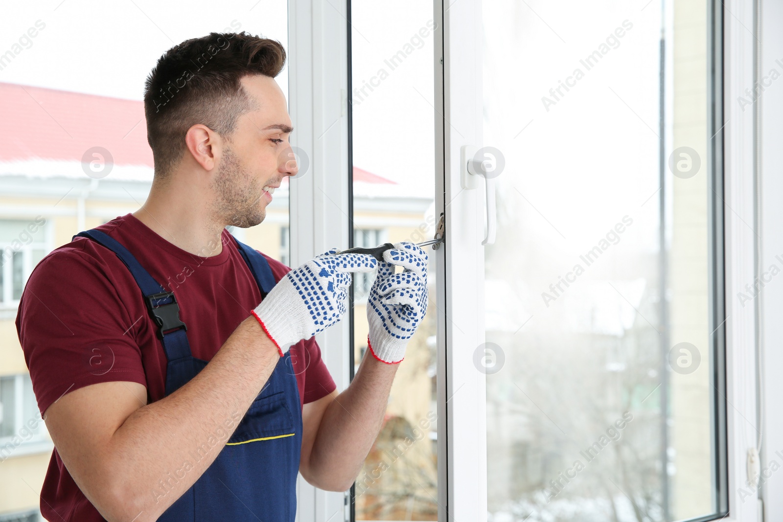 Photo of Construction worker adjusting installed window with screwdriver indoors