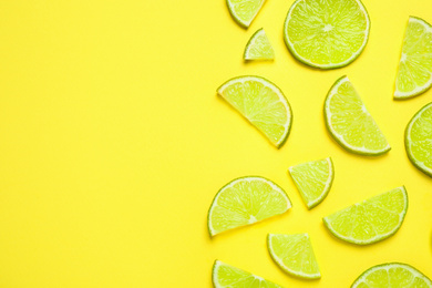 Photo of Juicy fresh lime slices on yellow background, flat lay. Space for text