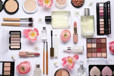 Photo of Flat lay composition with different makeup products and beautiful spring flowers on white background