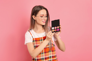Photo of Beauty blogger with brush and eyeshadow palette on pink background