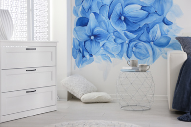 Photo of Stylish living room with blue flowers painted on wall. Floral pattern in interior design