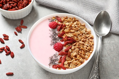 Photo of Smoothie bowl with goji berries and spoon on light grey table
