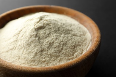 Photo of Bowl of agar-agar powder on black background, closeup