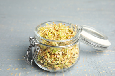 Photo of Glass jar with sprouted green buckwheat on grey wooden table