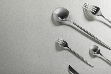 Photo of Forks, knife and spoons on grey background, flat lay with space for text. Stylish cutlery set