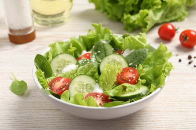 Delicious salad in bowl on white wooden table, closeup