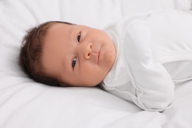 Cute newborn baby lying on white bed