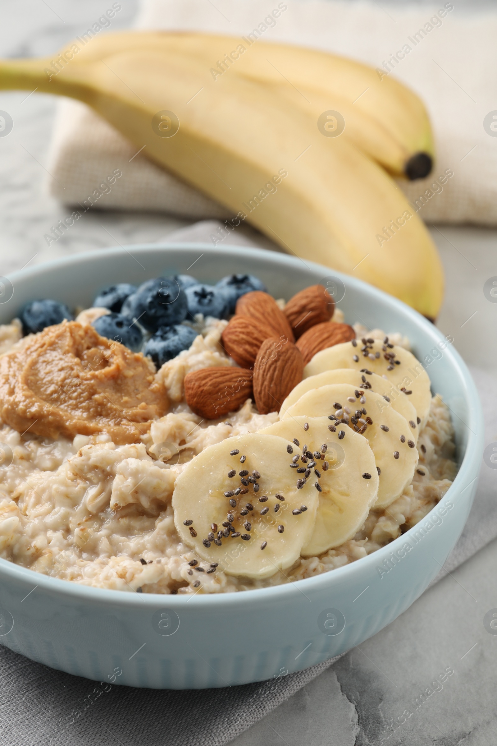 Photo of Tasty oatmeal porridge with toppings in bowl on table, closeup