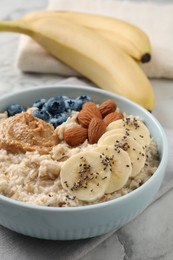 Photo of Tasty oatmeal porridge with toppings in bowl on table, closeup