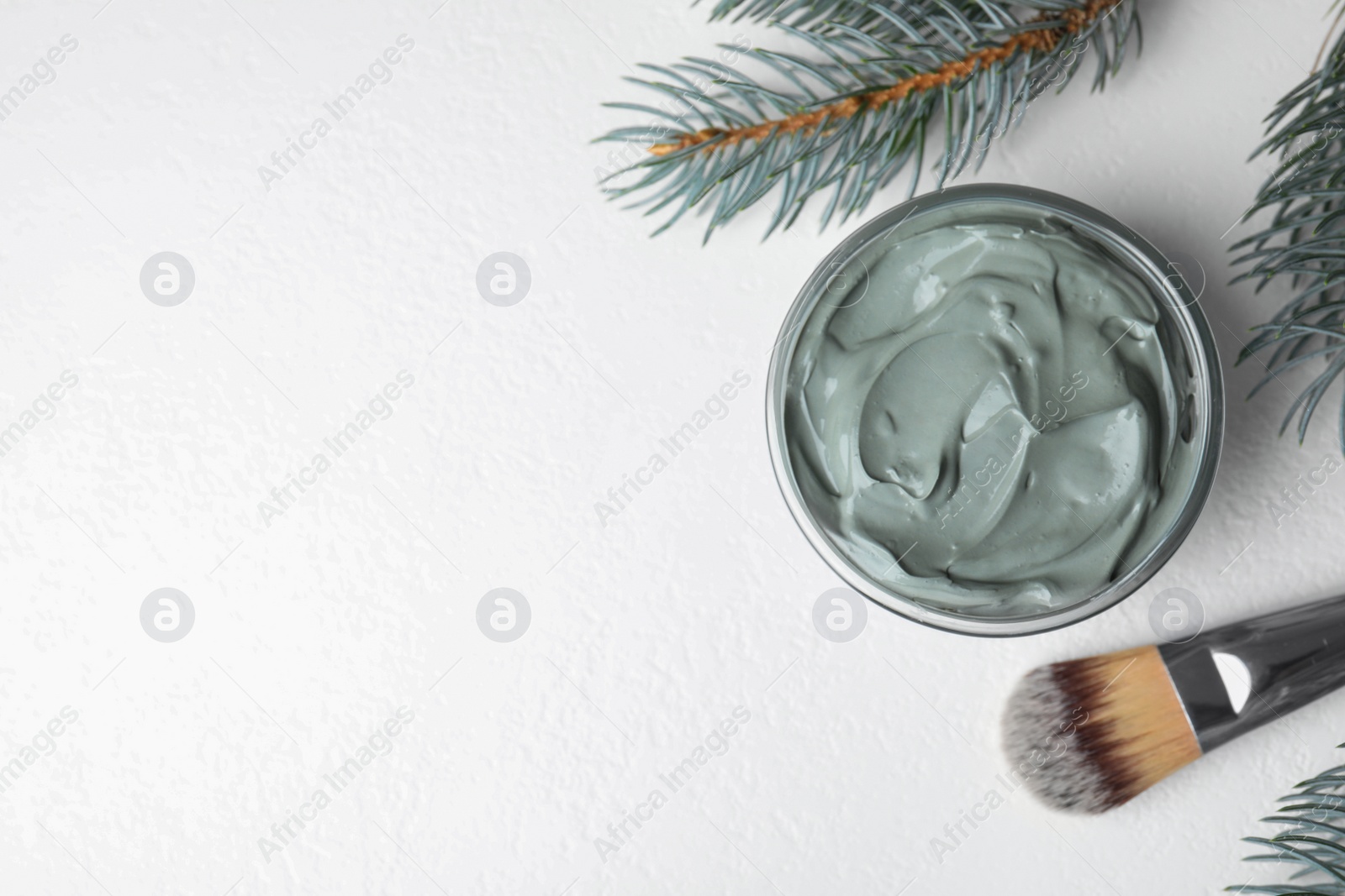 Photo of Professional face mask with spruce and brush on white table, flat lay. Space for text