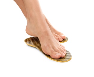 Photo of Woman fitting orthopedic insoles on white background, closeup. Foot care