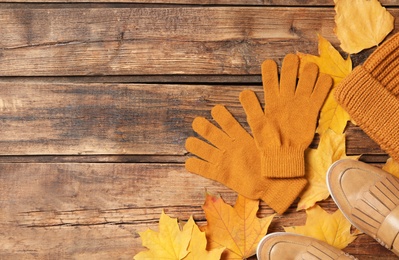Photo of Flat lay composition with stylish woolen gloves and dry leaves on wooden table. Space for text