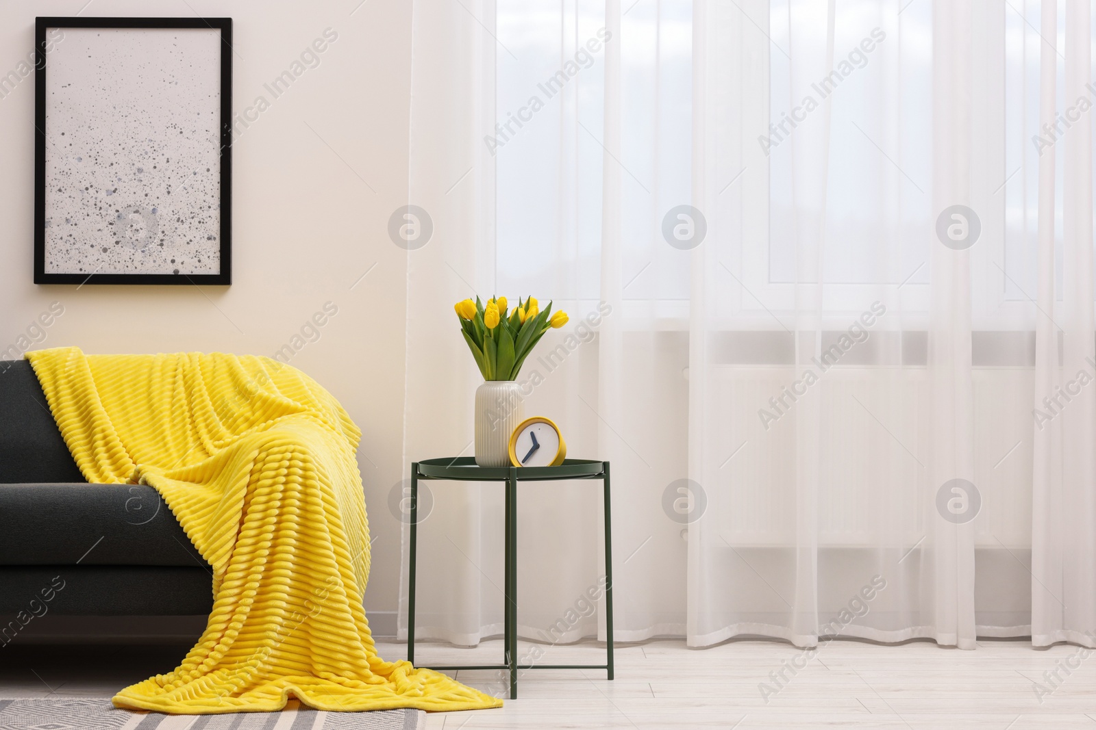 Photo of Spring atmosphere. Stylish living room interior with comfortable furniture and bouquet of beautiful yellow tulips