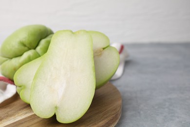 Photo of Cut and whole chayote on gray table, closeup. Space for text