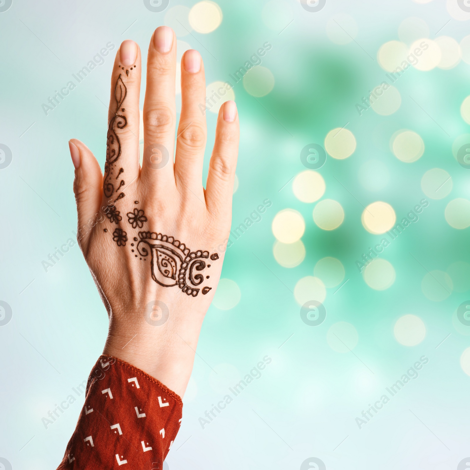 Image of Woman with henna tattoo on hand against blurred lights, bokeh effect. Space for text