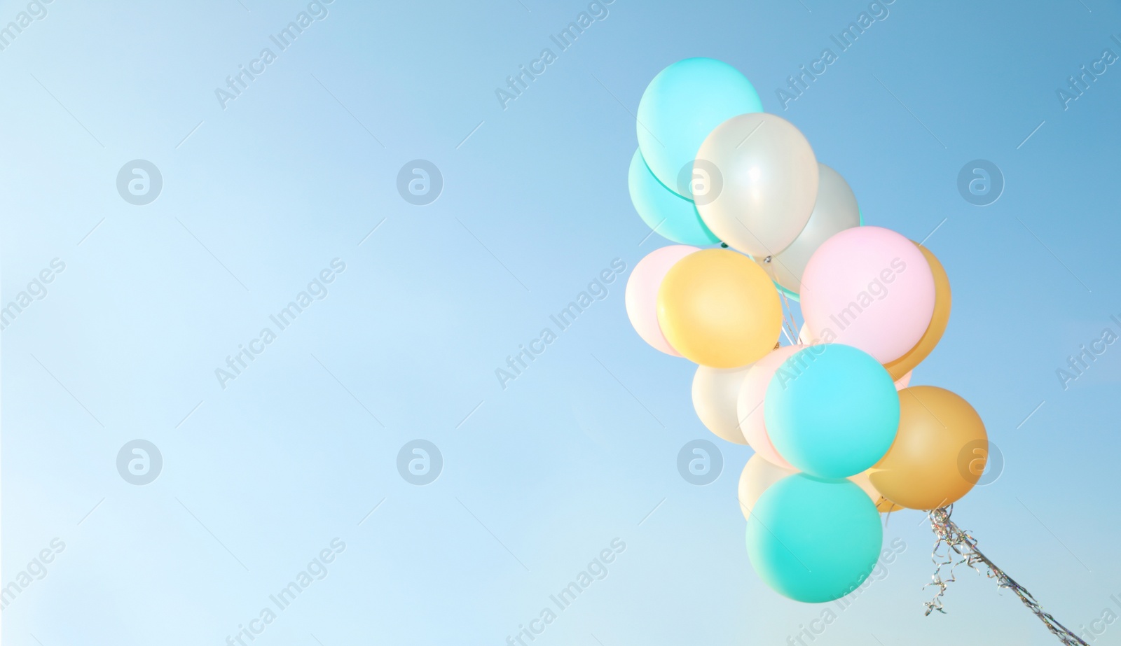 Photo of Bunch of colorful balloons against clear blue sky. Space for text