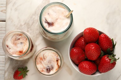 Photo of Tasty yoghurt with jam and strawberries on white wooden table, top view