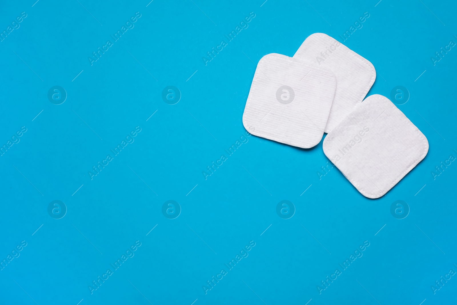 Photo of Cotton pads on light blue background, flat lay. Space for text