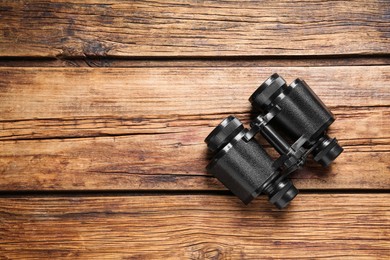 Photo of Binoculars on wooden table, top view. Space for text
