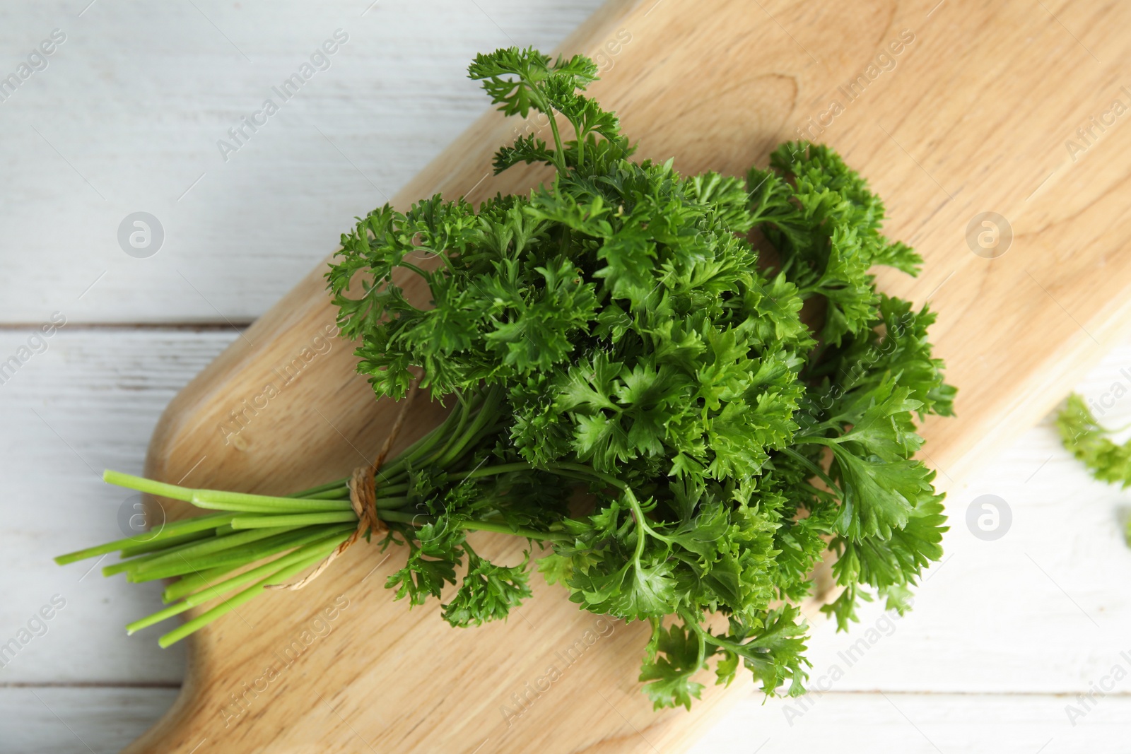 Photo of Wooden board with fresh green parsley on table, top view