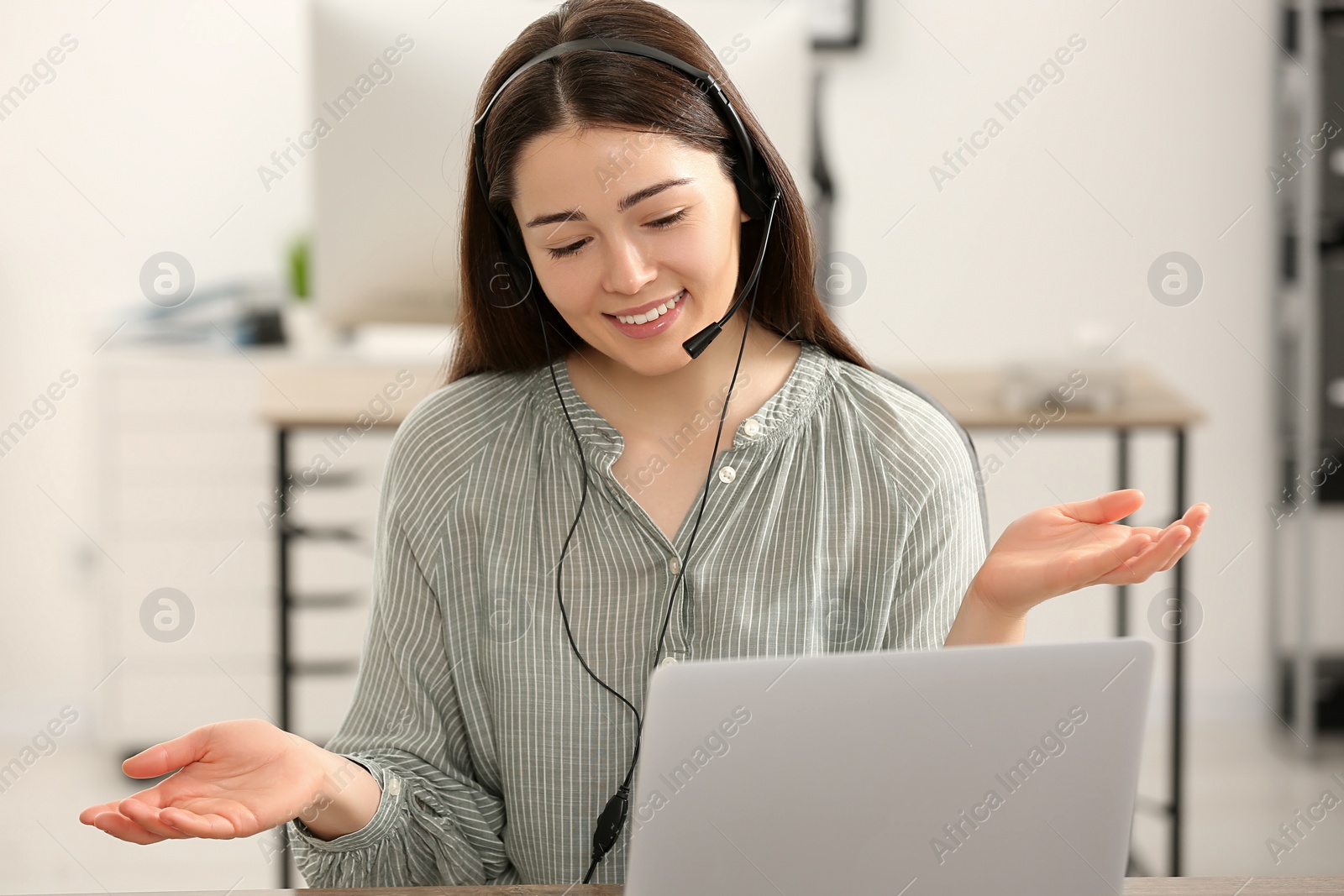 Photo of Hotline operator with headset working on laptop in office