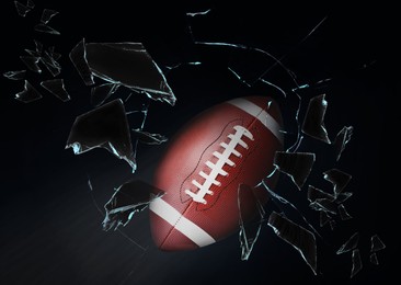 Image of American football ball breaking up glass against black background