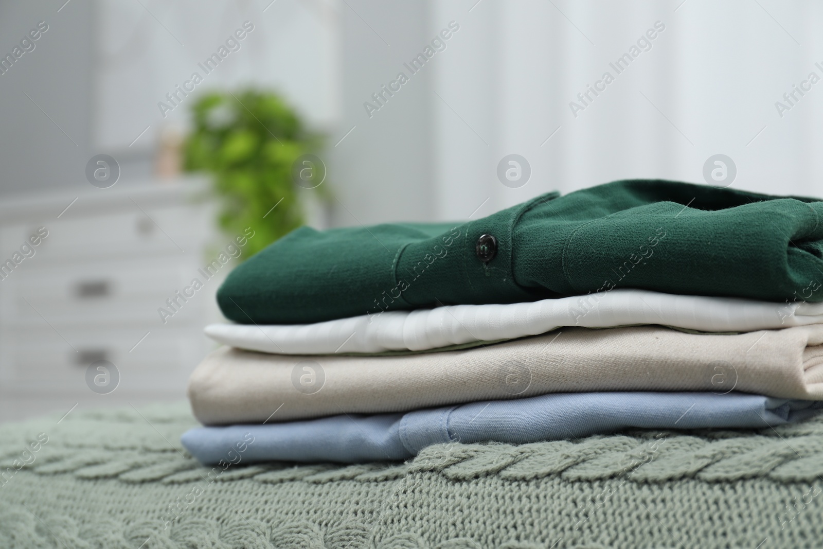 Photo of Sorting and organizing. Stack of different folded clothes on bed indoors, space for text