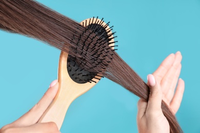 Woman with hair brush on color background, closeup